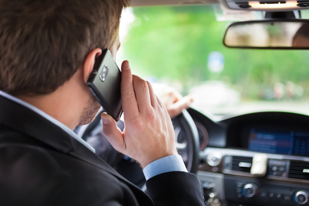 man on phone driving with Car Insurance in Saginaw, Michigan