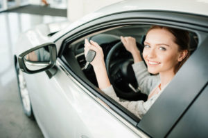 Auto insurance in Bay City, MI, with smiling female driver in a car