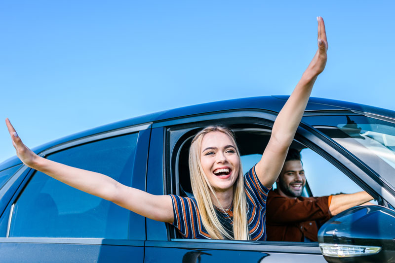 Woman and man happily driving with Cheap Car Insurance in Saginaw, MI